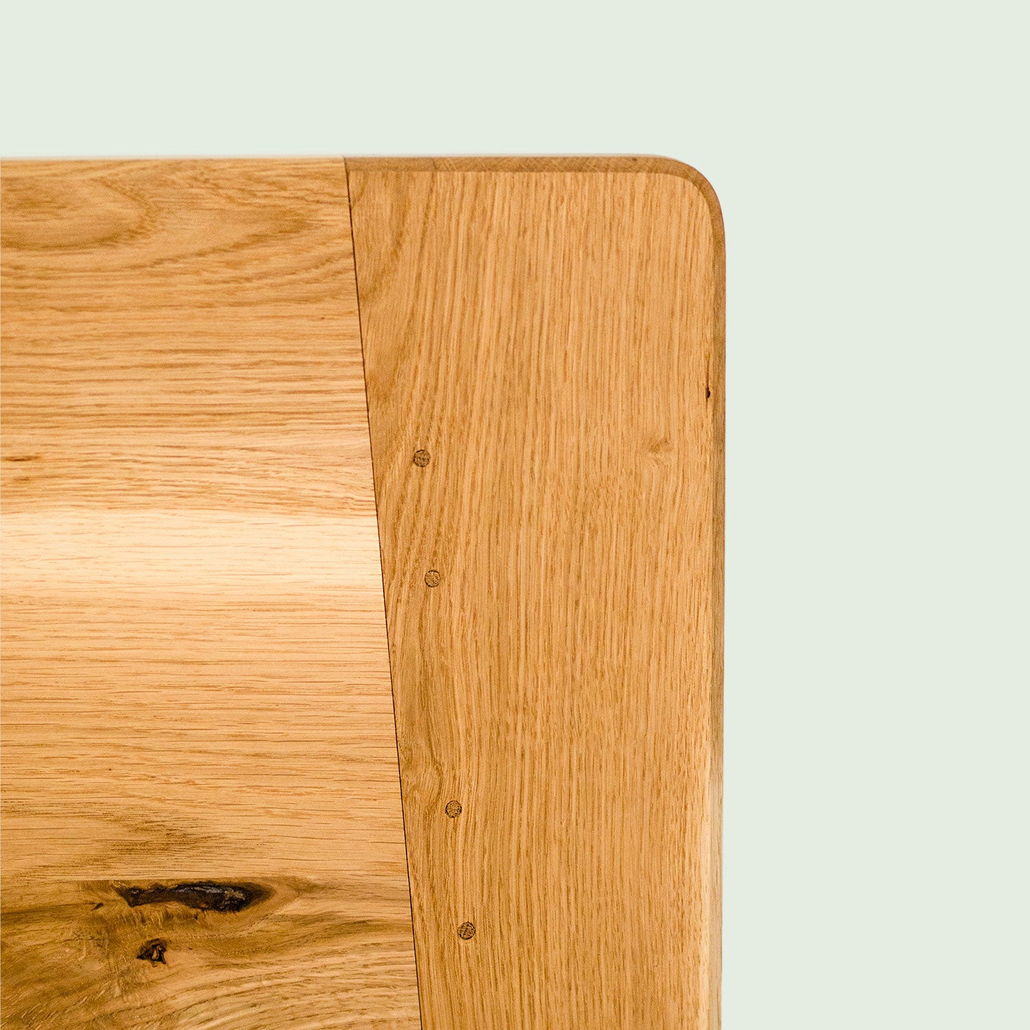 Nahaufnahme des Kopfteils vom Bett Norderney, gefertigt aus regionalem Eichenholz mit traditionellen Verbindungen. Die Ecke des Kopfteils ist stark verrundet und minimalistisch gestaltet.