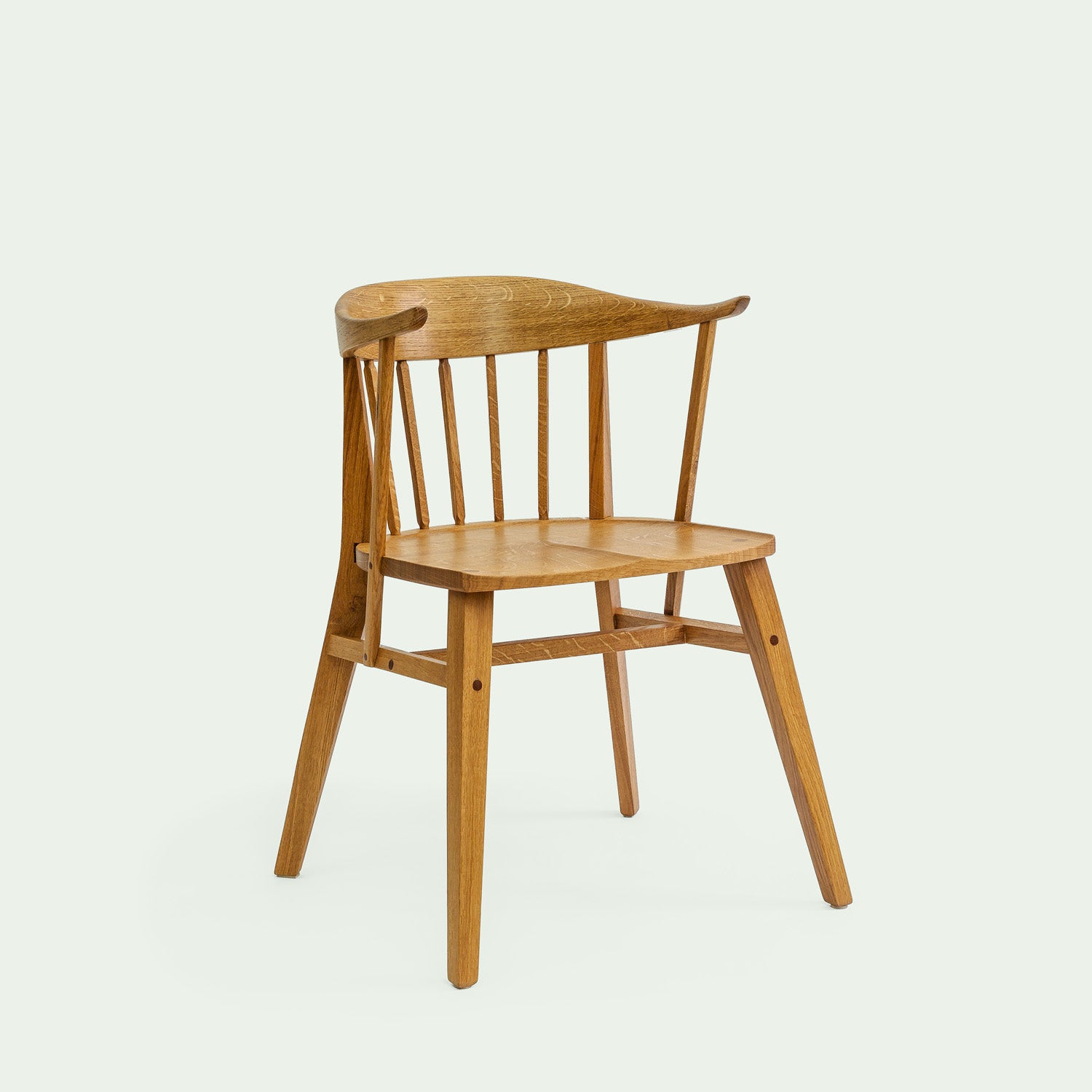 Holzstuhl Norderney in seitlicher Ansicht. Der Stuhl hat eine geschwungene Rückenlehne und schmale, abgerundete Beine, die leicht nach außen ausgestellt sind. Die Rückenlehne ist mit mehreren senkrechten Holzstreben versehen, die von der Sitzfläche bis zur oberen Kante der Lehne reichen.