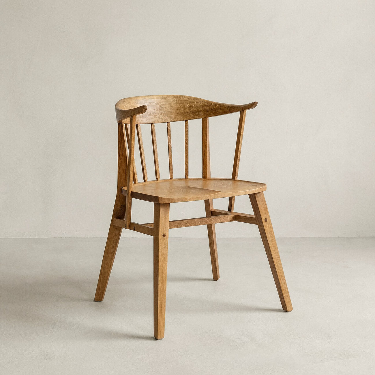 Holzstuhl Norderney in seitlicher Ansicht. Der Stuhl hat eine geschwungene Rückenlehne und schmale, abgerundete Beine, die leicht nach außen ausgestellt sind. Die Rückenlehne ist mit mehreren senkrechten Holzstreben versehen, die von der Sitzfläche bis zur oberen Kante der Lehne reichen.