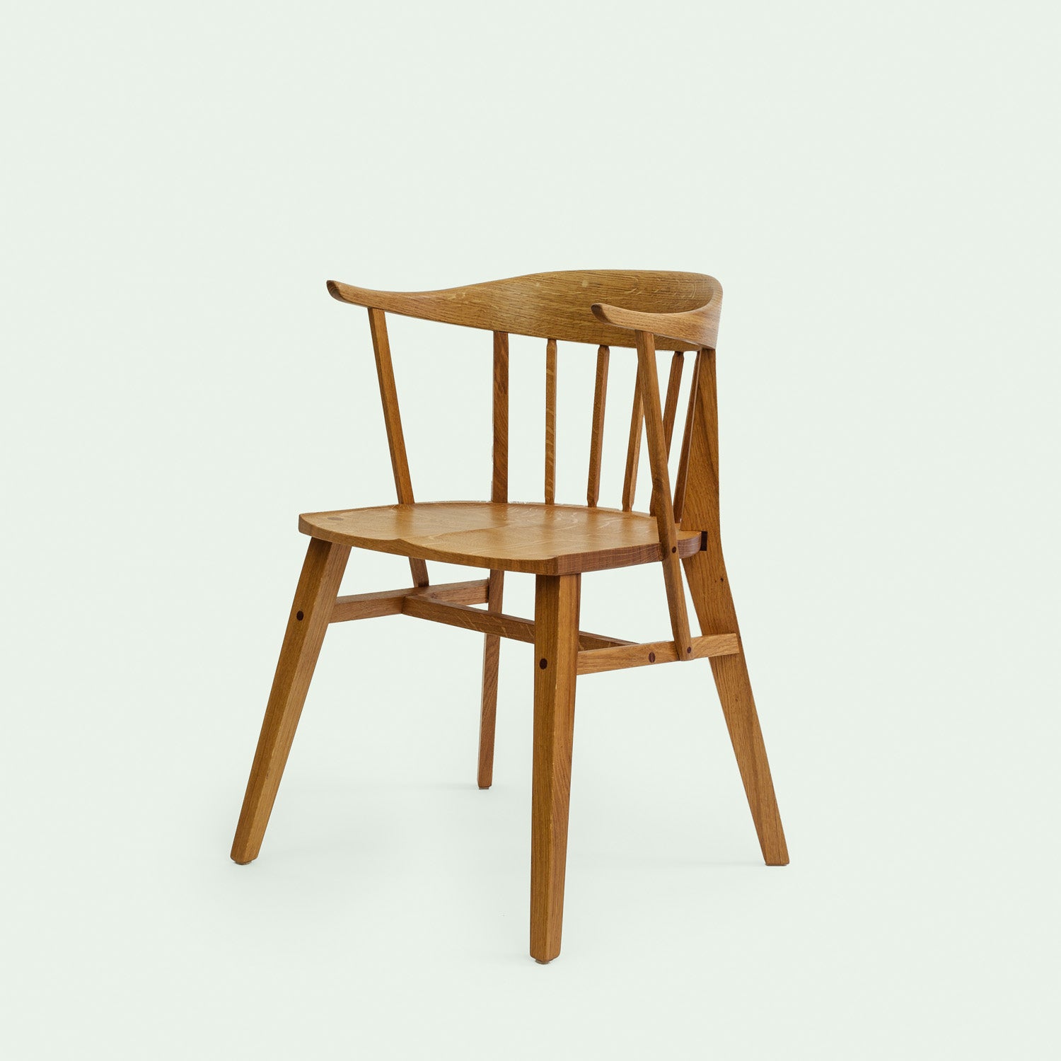 Eine diagonale Ansicht des Eichenholzstuhl Norderney, die die Konstruktion und die geschwungene Form der Rückenlehne sowie die Stabilität der Beine hervorhebt.
