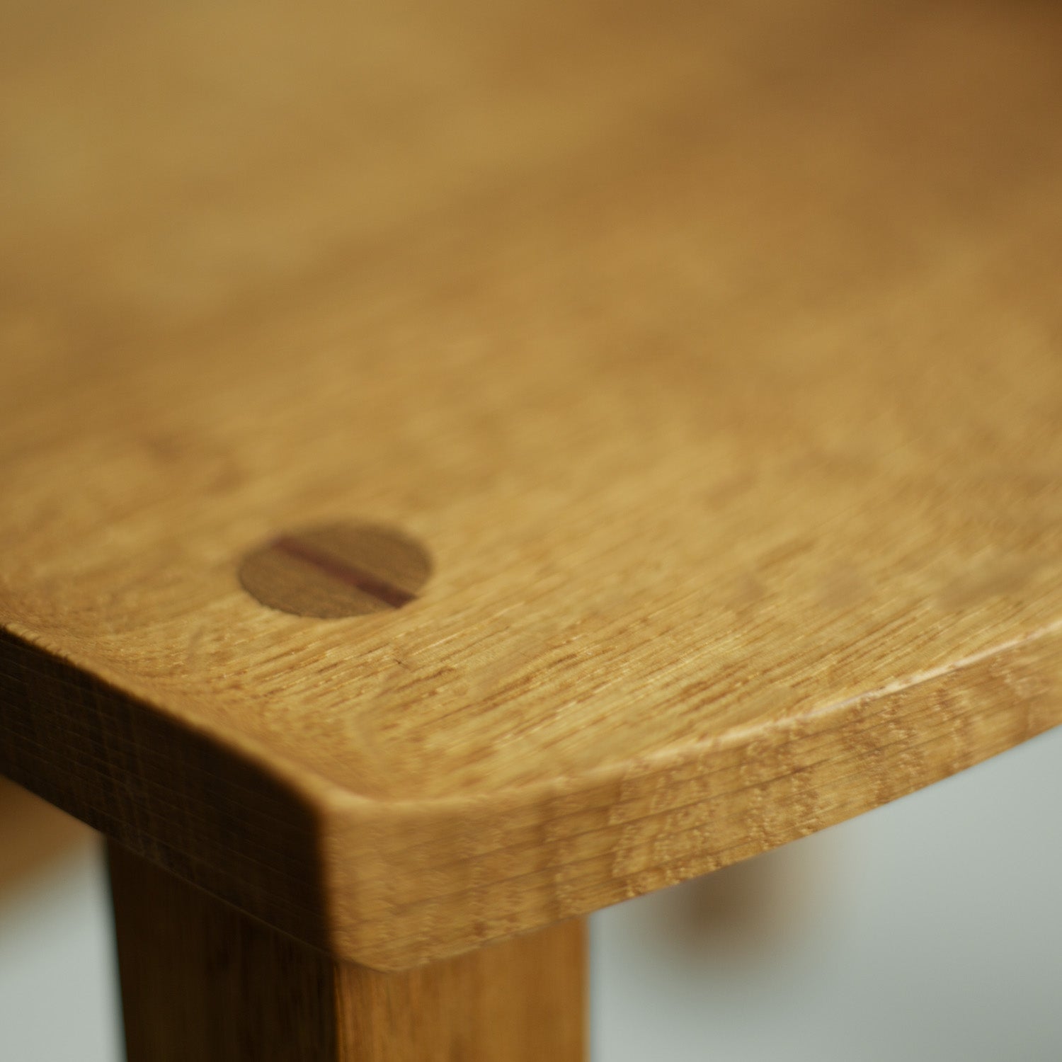 Eine Nahaufnahme eines Teils der Sitzfläche des Holzstuhl Norderney, die die feine Holzmaserung und die glatte Oberfläche des Eichenholzes zeigt.