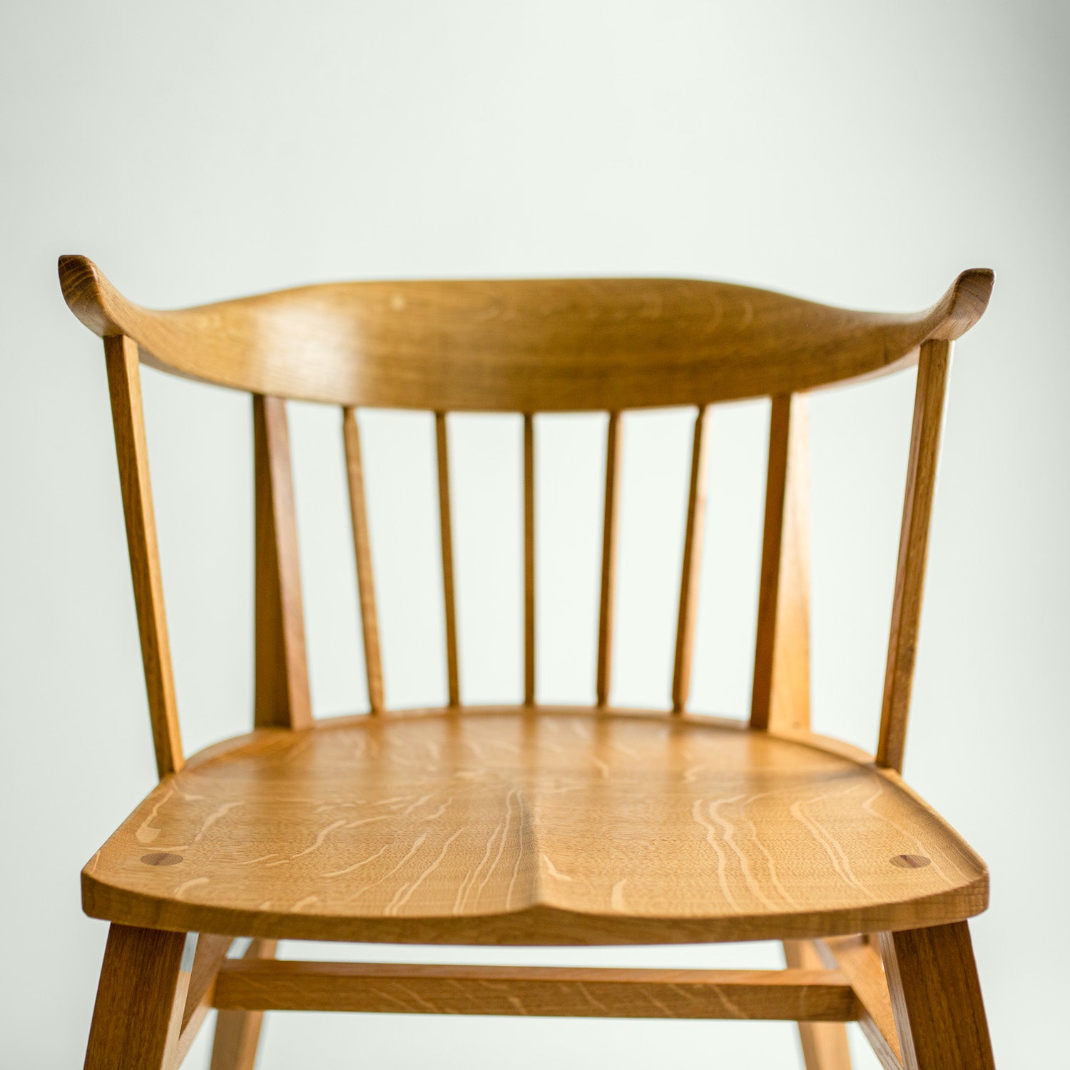 Eine Nahaufnahme des Eichenholz Stuhl Norderney, die die Details der Holzmaserung und die handwerkliche Verarbeitung der Sitzfläche und der Rückenlehne zeigt.