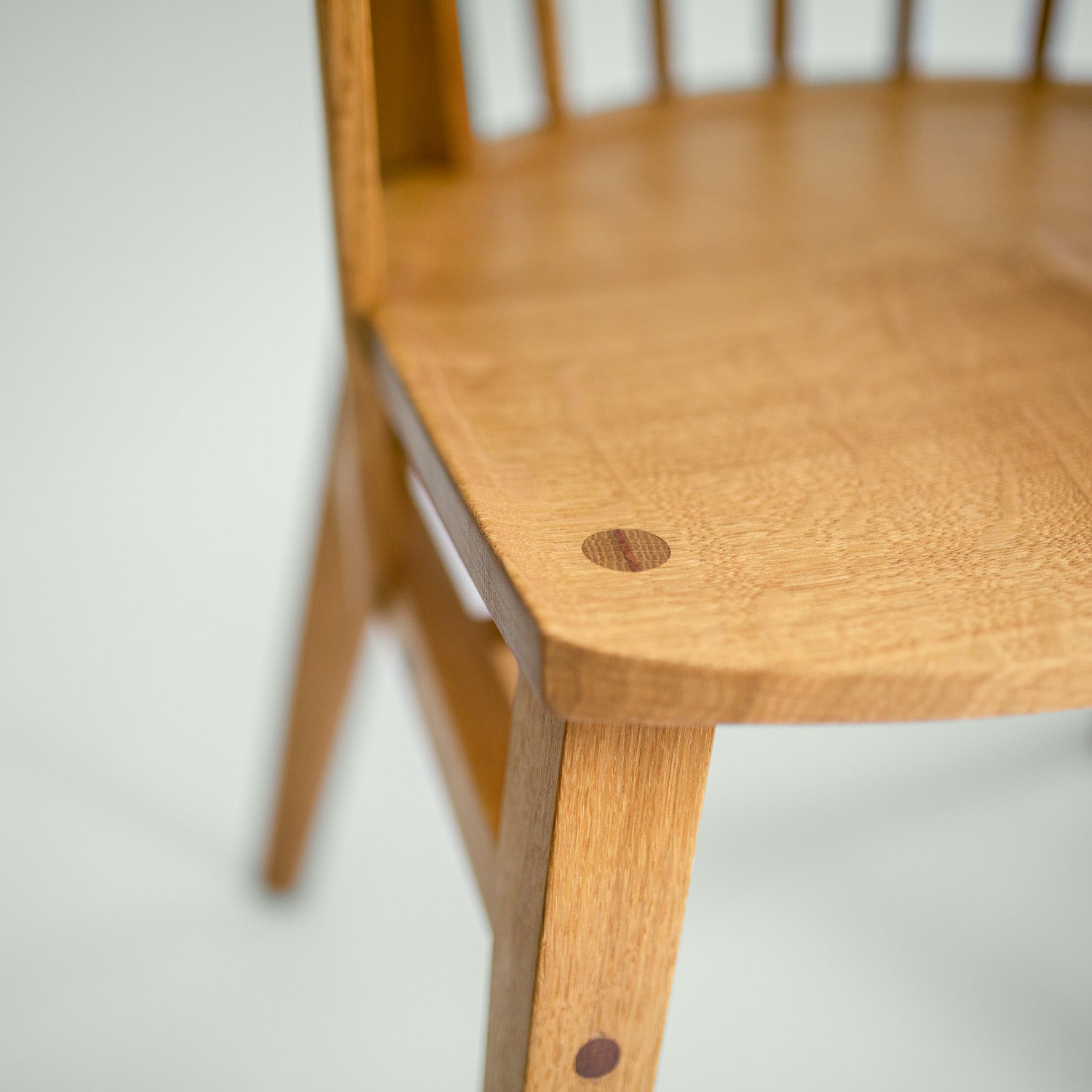 Detailaufnahme der Sitzfläche und der traditionellen Verbindungen des Stuhl Norderney, aus Eichenholz und Kirsche gefertigt.