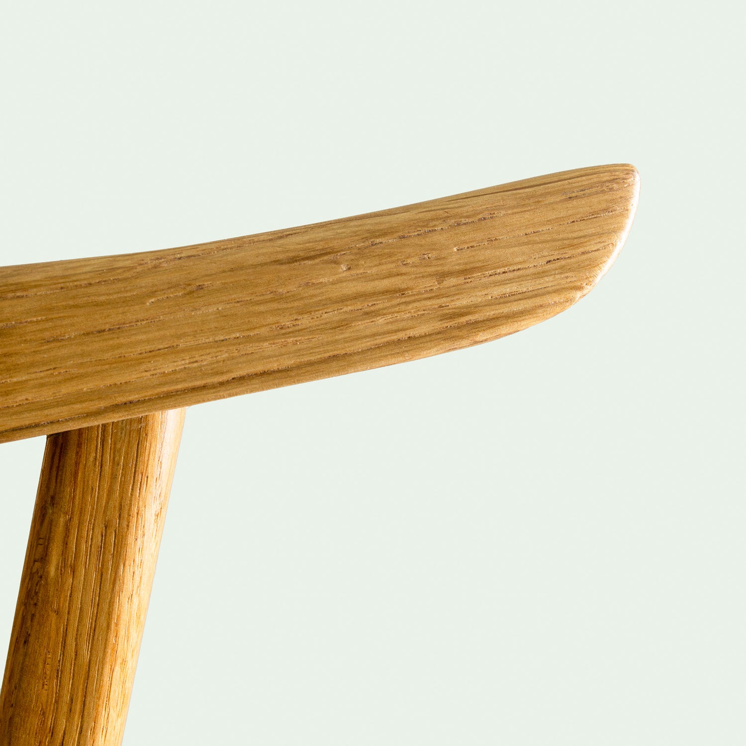 Eine Nahaufnahme eines Teils der Rückenlehne des Eichenholzstuhles Norderney, die die feine Holzmaserung und die glatte Oberfläche des Holzes zeigt.