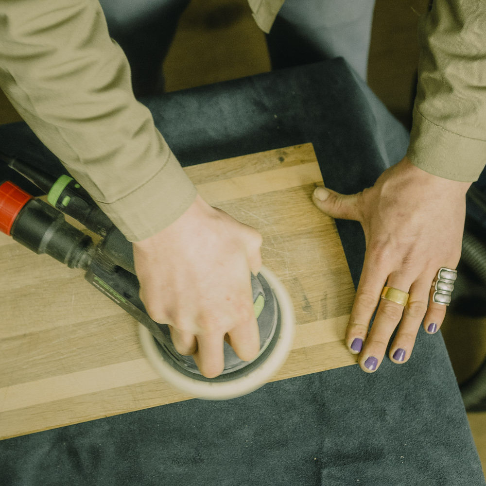 Holz richtig schleifen, ein Holzschneidebrett wird mit einer Schleifmaschine geschliffen