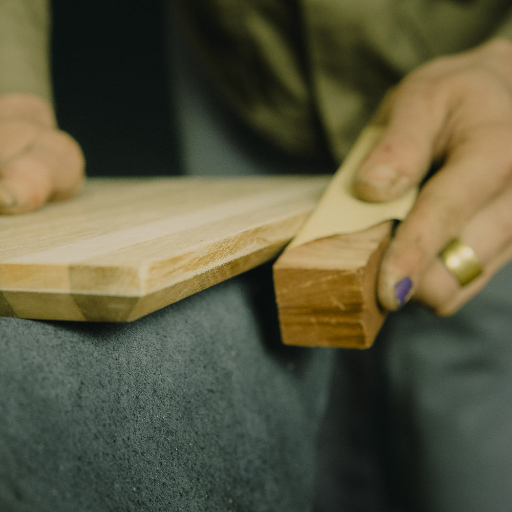 Ein Holzschneidebrett wird zur Holzpflege an den Kanten geschliffen