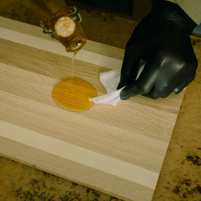 Öl wird zur richtigen Holzpflege auf ein Holzschneidebrett aufgetragen