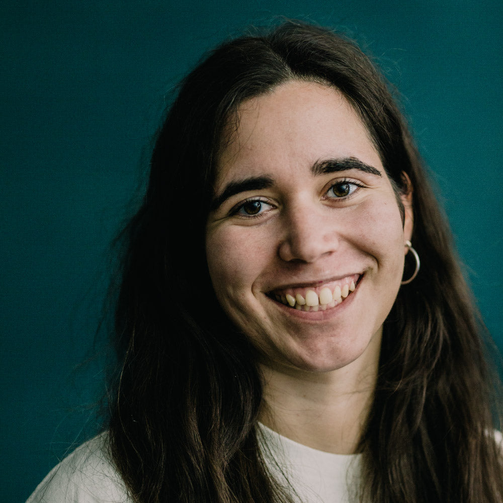 Porträt von Pauline Simon von mimikry in leipzig. Dunklen Haaren und Ohrringen, die direkt in die Kamera lächelt.