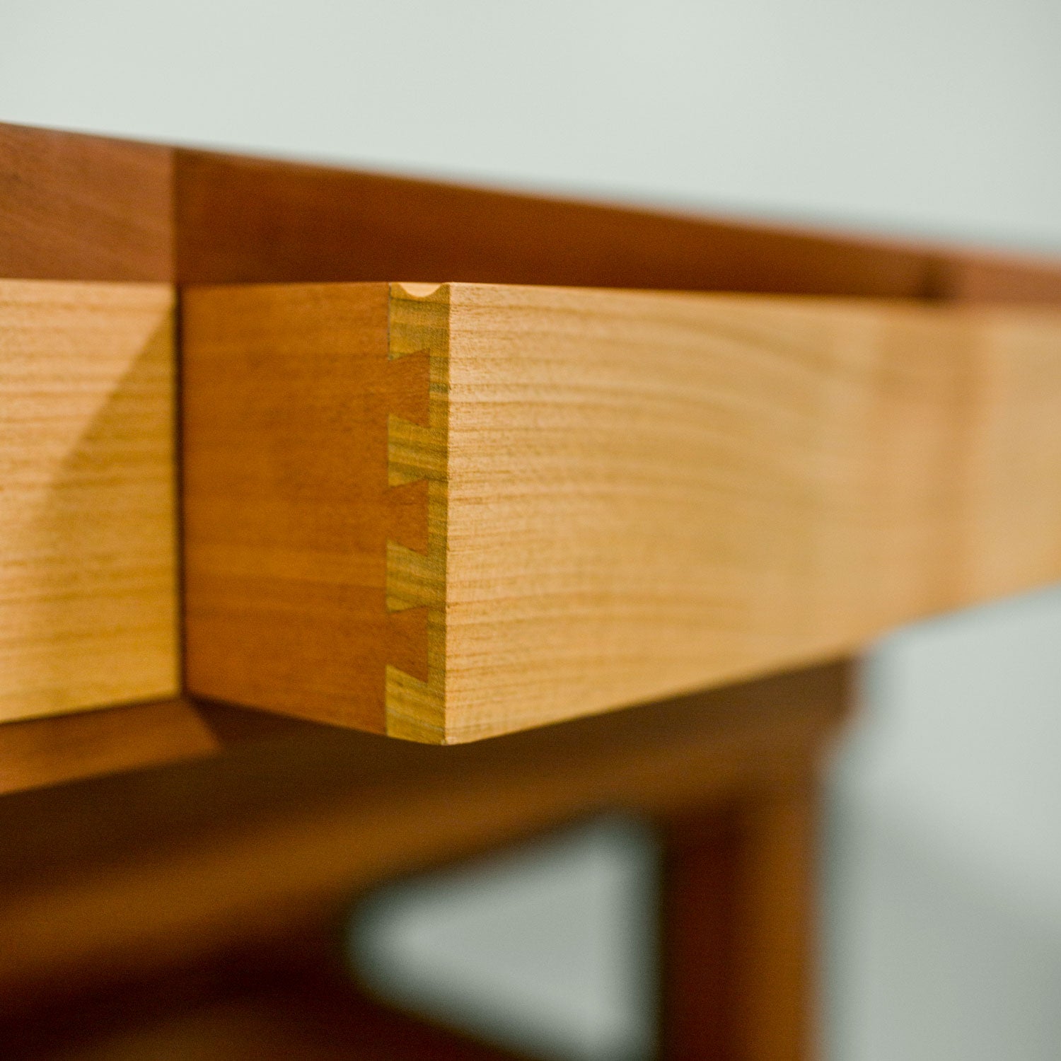 Detailaufnahme der Eckverbindung einer Schublade aus Holz mit Zinkenverbindung. Sie ist Teil des Spieletisches Corbin. Einer Sonderanfertigung.