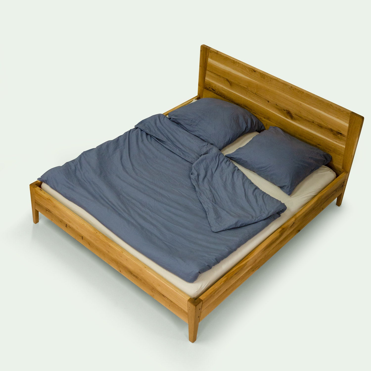 diagonale, erhöhte Ansicht des Holzbett Norderney von der Marke mimikry aus Leipzig. Mit Matratze und blauer Bettwäsche