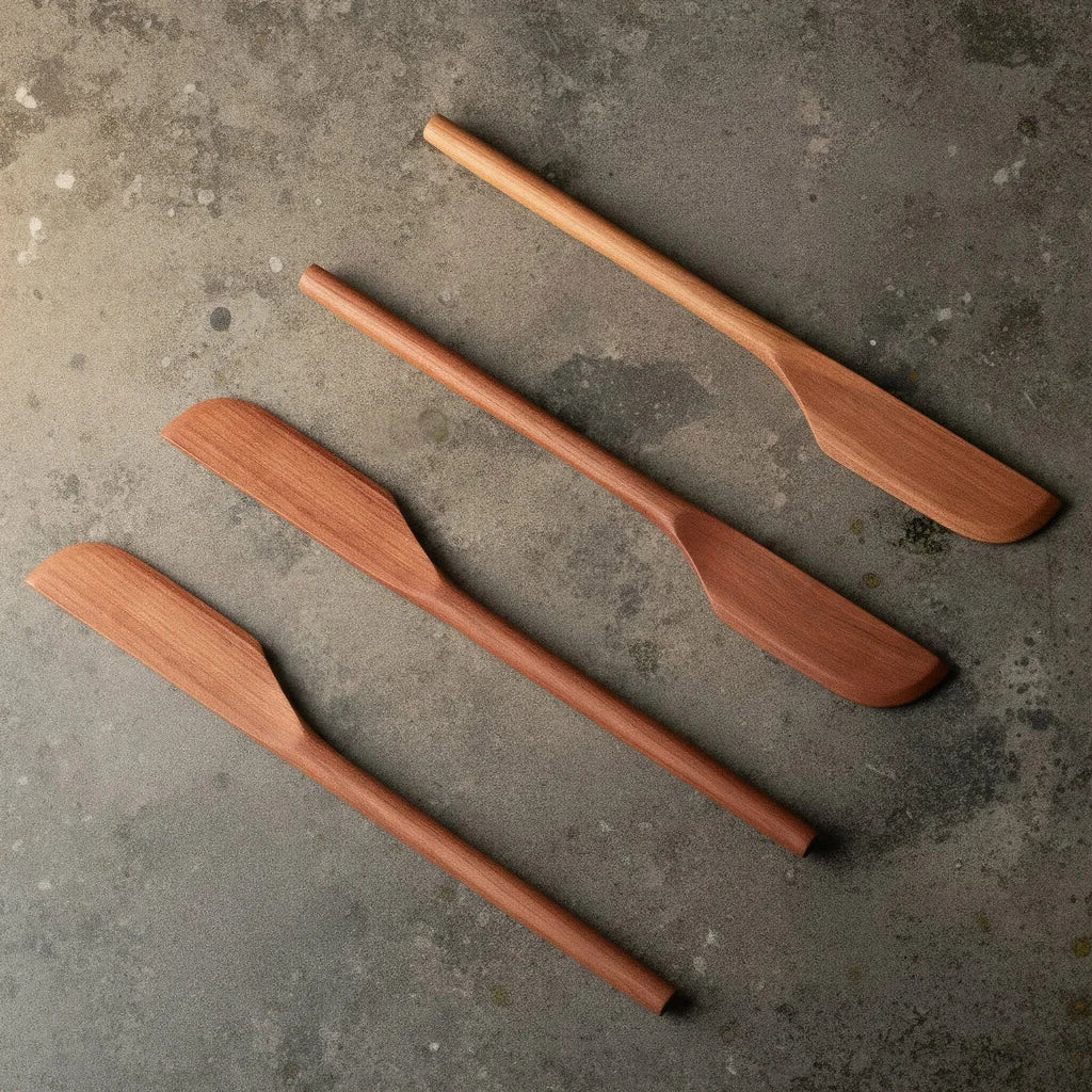 Buttermesser aus Holz, aus Elsbeerenholz gefertigt von Leipziger Tischlerei mimikry liegen vierfach nebeneinander als Materialbeispiel, denn jedes Holzmesser hat seine eigene Maserung und Erscheinungsbild, von warm rot bis gelblich gold