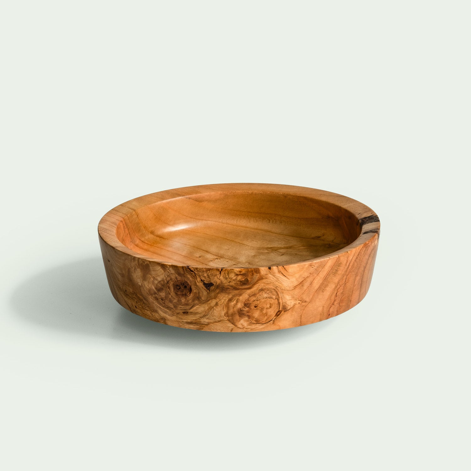 Eine handgefertigte Holzschale aus verwurzeltem Kirschholz mit einzigartiger Maserung steht im Raum und wird von oben betrachtet.