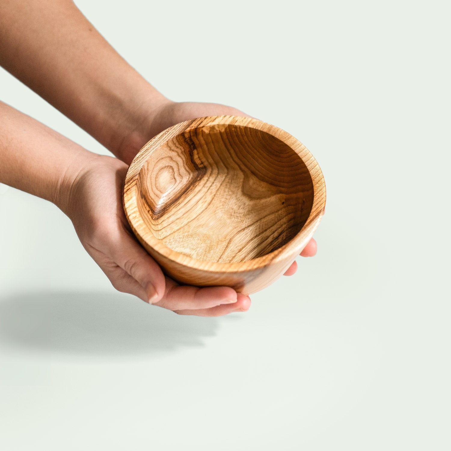 Hand hält eine handgefertigte Schale aus Rüsterholz mit rustikaler Schönheit und natürlicher Holzmaserung.