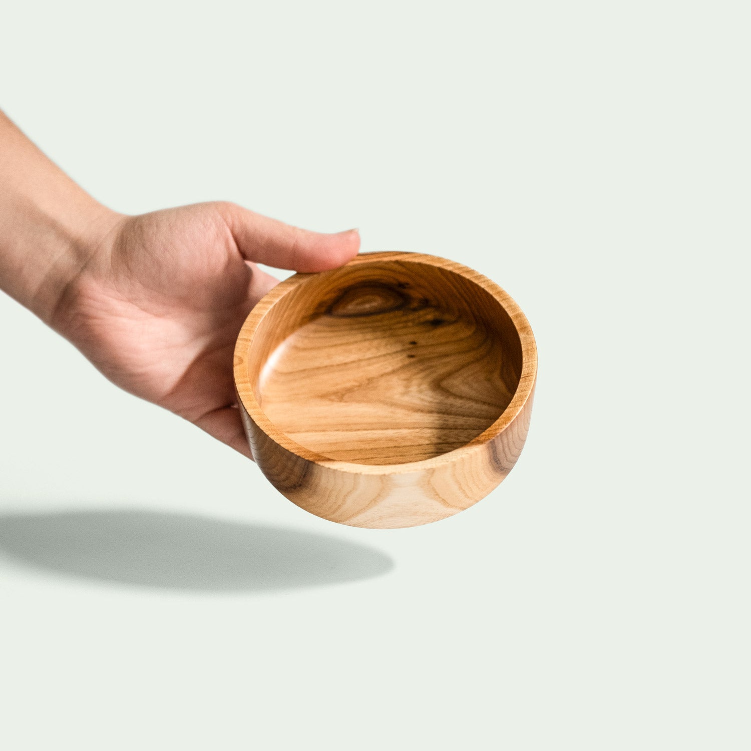 Hand hält eine handgefertigte Schale aus Rüsterholz mit rustikaler Schönheit und natürlicher Holzmaserung.