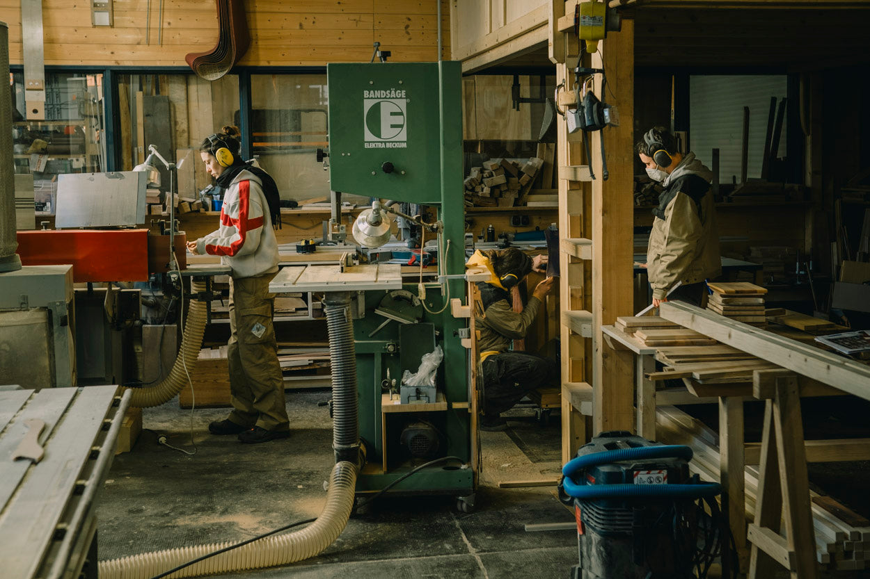 Drei Tischler:innen bei der Arbeit in der Werkstatt – Teamarbeit und Handwerkskunst in Leipziger Tischlerei