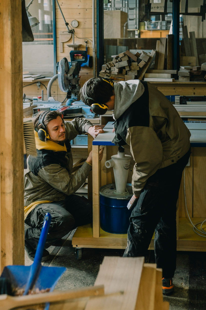 Team aus Tischlern fertigt gemeinsam ein großes Möbelstück aus Massivholz