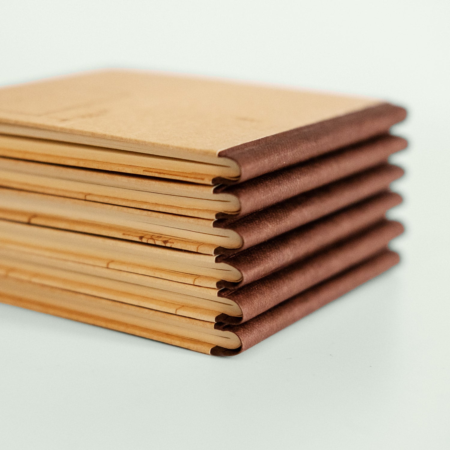 Ein Detailfoto zeigt die Buchrücken von sechs handgefertigten Notizbüchern, die in einer Reihe gestapelt sind und die Präzision der Verarbeitung hervorheben.