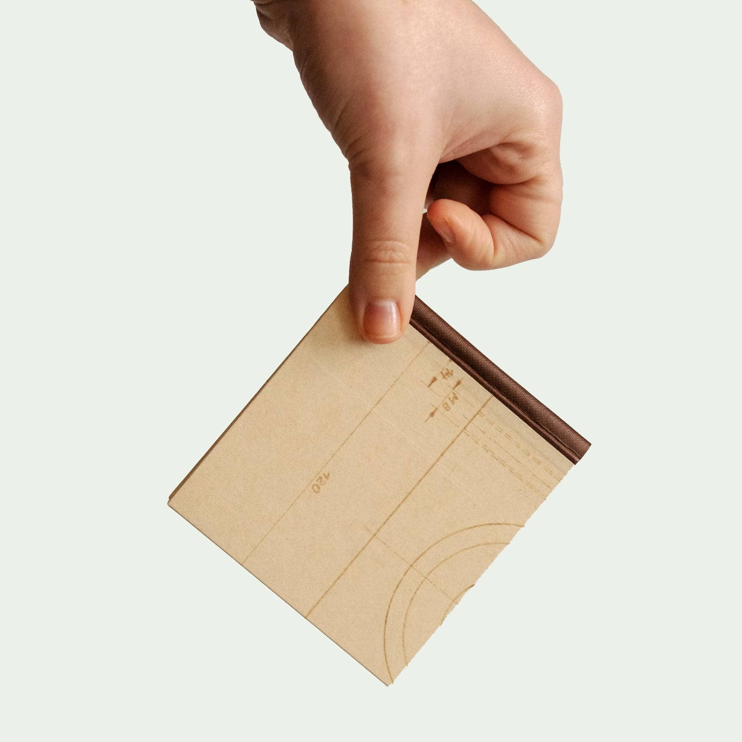 Ein handgefertigtes Notizbuch wird in der Hand gehalten und zeigt das Design des Einbands mit geometrischen Mustern und technischen Zeichnungen.