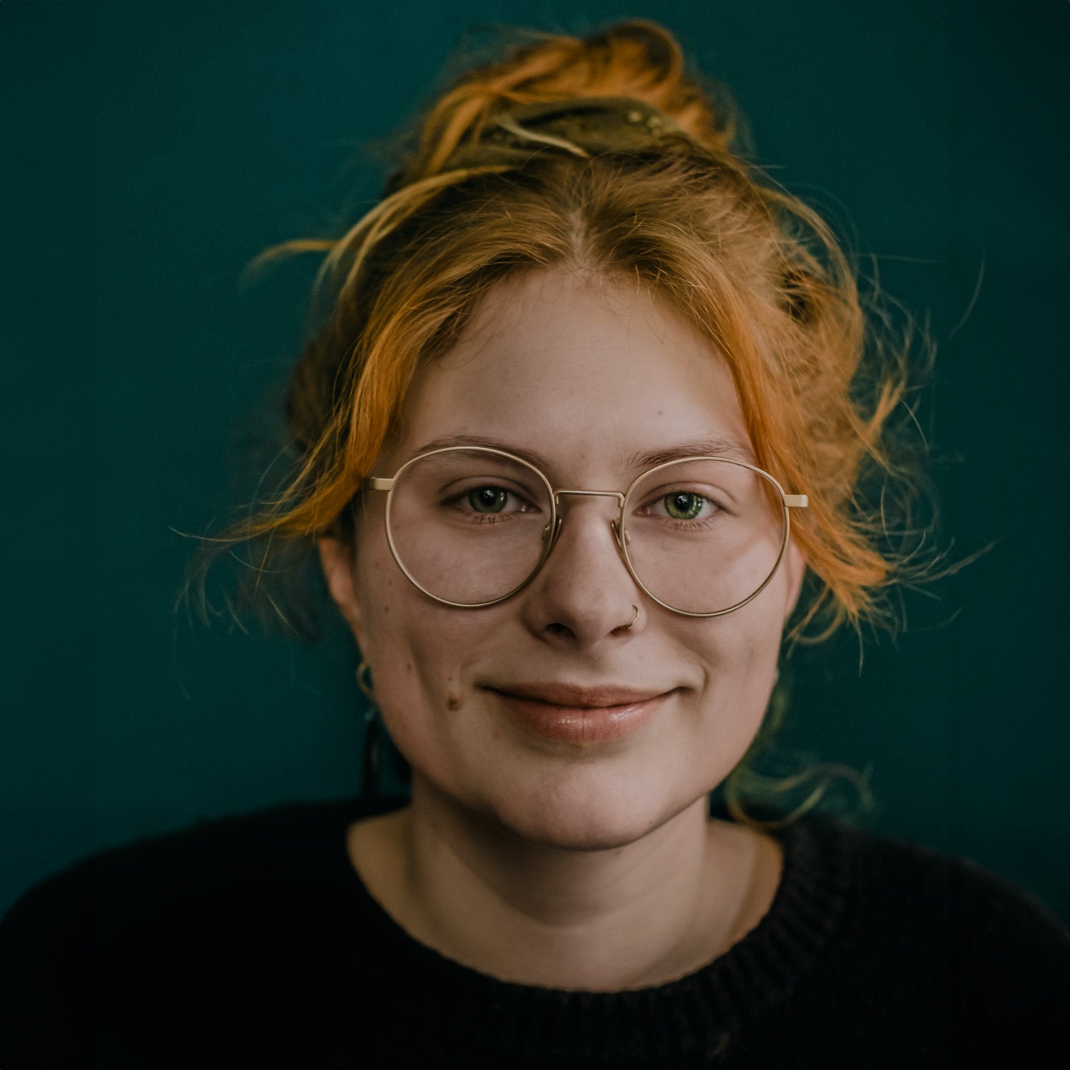 Porträt von Pauline Gutschow von mimikry mit kurzem, blonden Haar und großen Ohrringen, die lächelt und den Blick gesenkt hat.