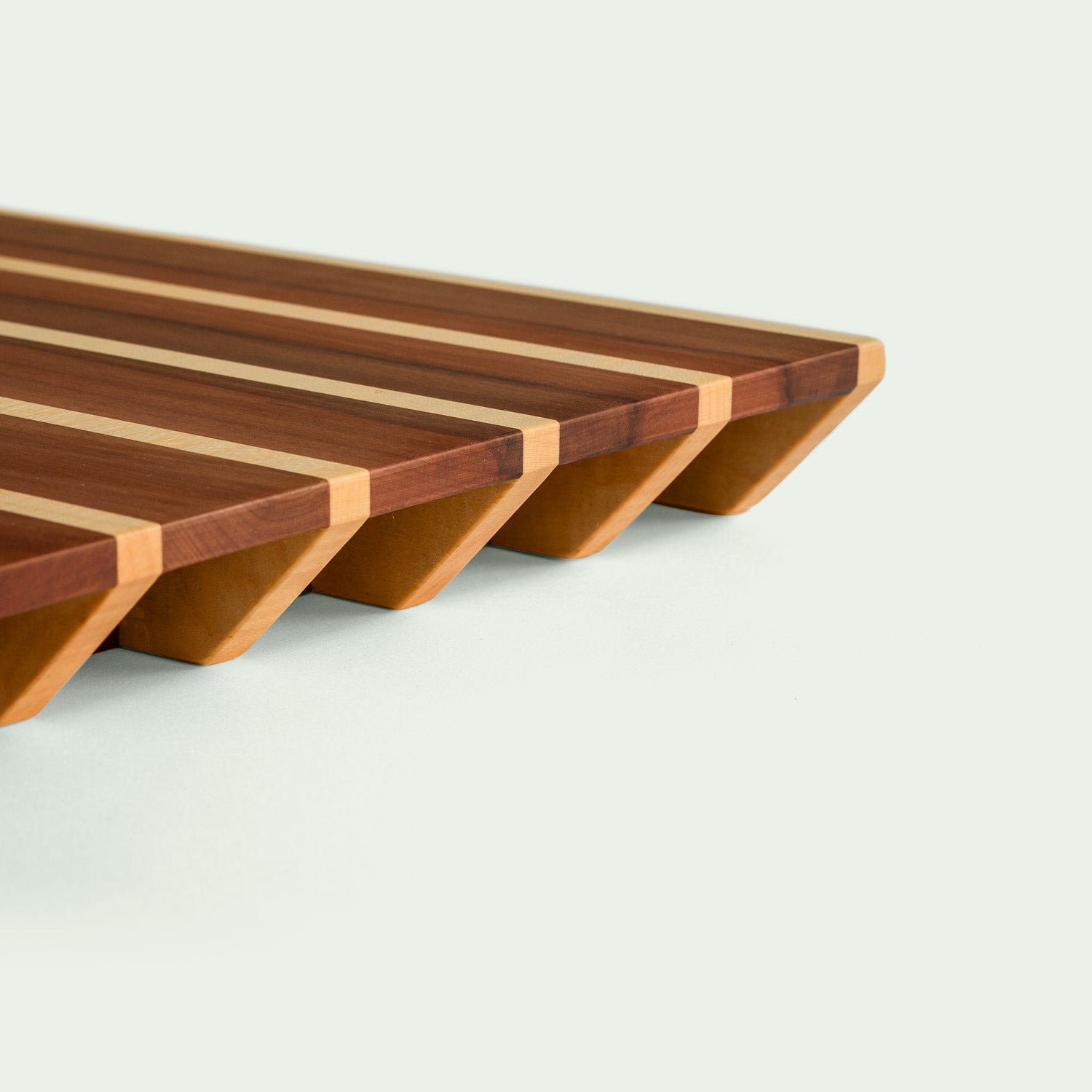 Detailansicht der Unterkante eines Holzschneidebretts mit gestreiftem Muster aus Ahorn und Elsbeere