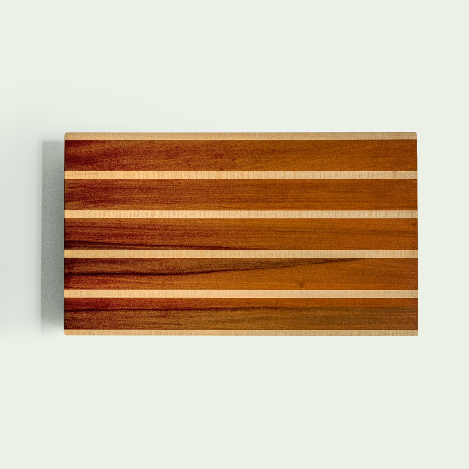 Schneidebrett aus Holz mit gestreiftem Muster aus Ahorn und Elsbeere in Vogelperspektive.