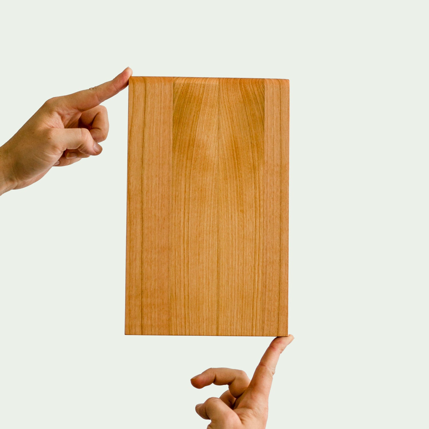 Frühstückbrett aus Kirsch Holz wird elegant auf zwei fingern ins Bild gehalten