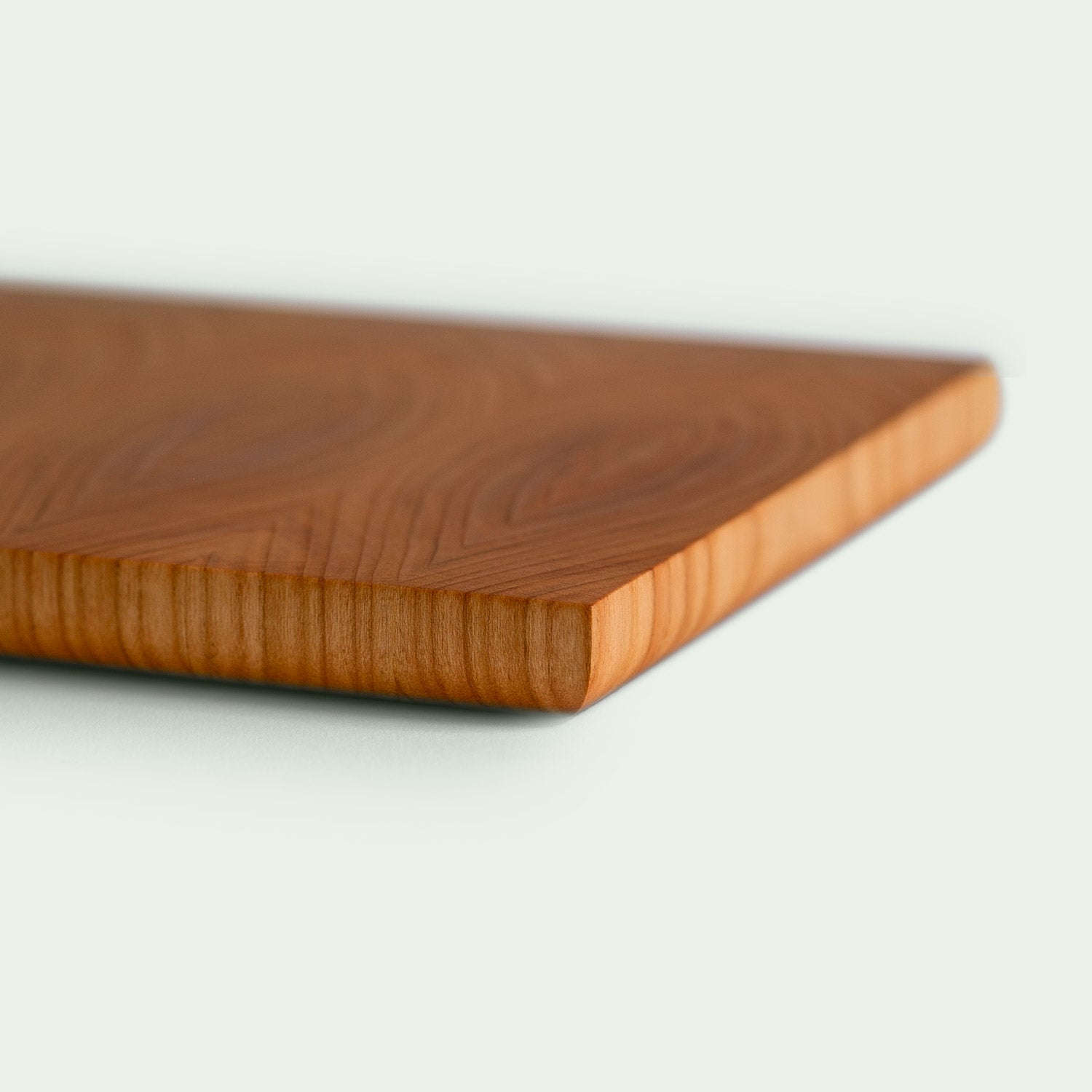 Eine Detailansicht eines Hirnholz Schneidebrett aus Kirsche. Mit Blick auf die verrundete Unterkante des Schneidebrettes