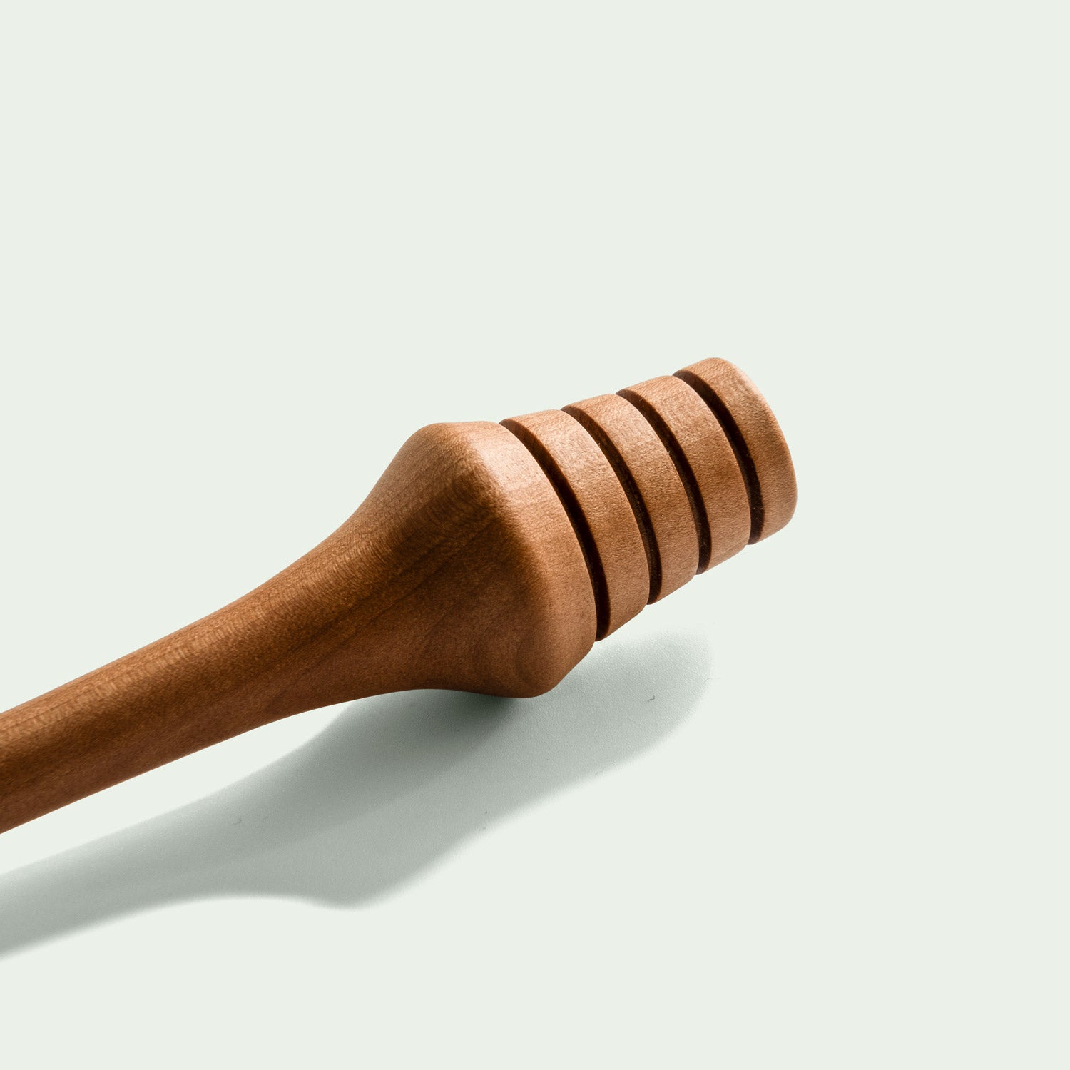 Ein Detailfoto eines Honiglöffels aus der Serie "Elsbeere", der das fein gearbeitete Holz und die Rillen zur Honigaufnahme zeigt.