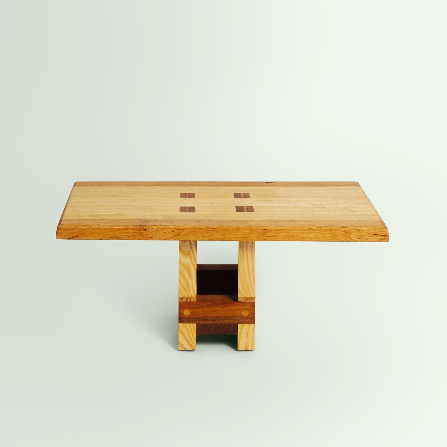 Frontalansicht des Meditationshockers "Medi". Der Hocker hat eine rechteckige Sitzfläche und robuste, blockartige Beine, die eine stabile Basis bilden. Das Design ist schlicht und funktional, mit klaren Linien und natürlichen Holzmaserungen.