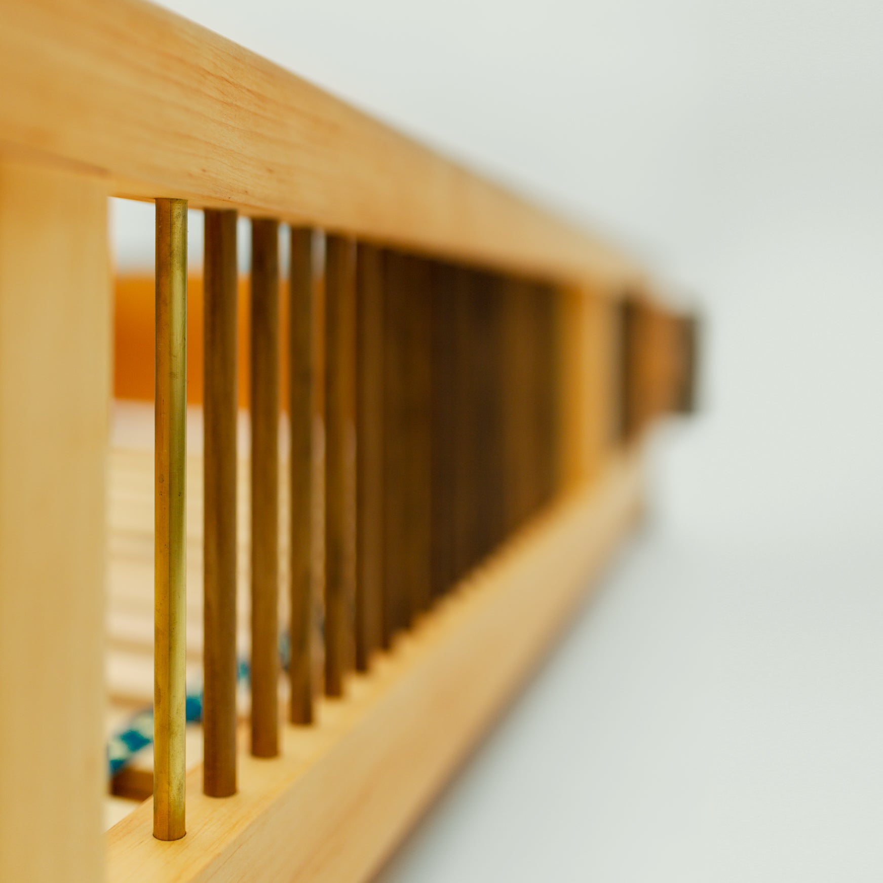 Nahaufnahme der Bettkante des Bettes "Liam", die die geschwungene Form und die stabile Verbindungstechnik zwischen Esche und Walnuss zeigt.