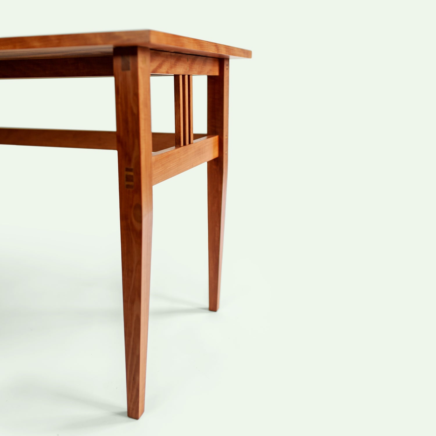 Dieses Bild zeigt die schlanken Tischbeine und die stabile Konstruktion der Tischunterseite aus Elsbeere. Die Tischplatte besteht aus Apfelholz und verleiht dem Tisch eine elegante und natürliche Ästhetik.