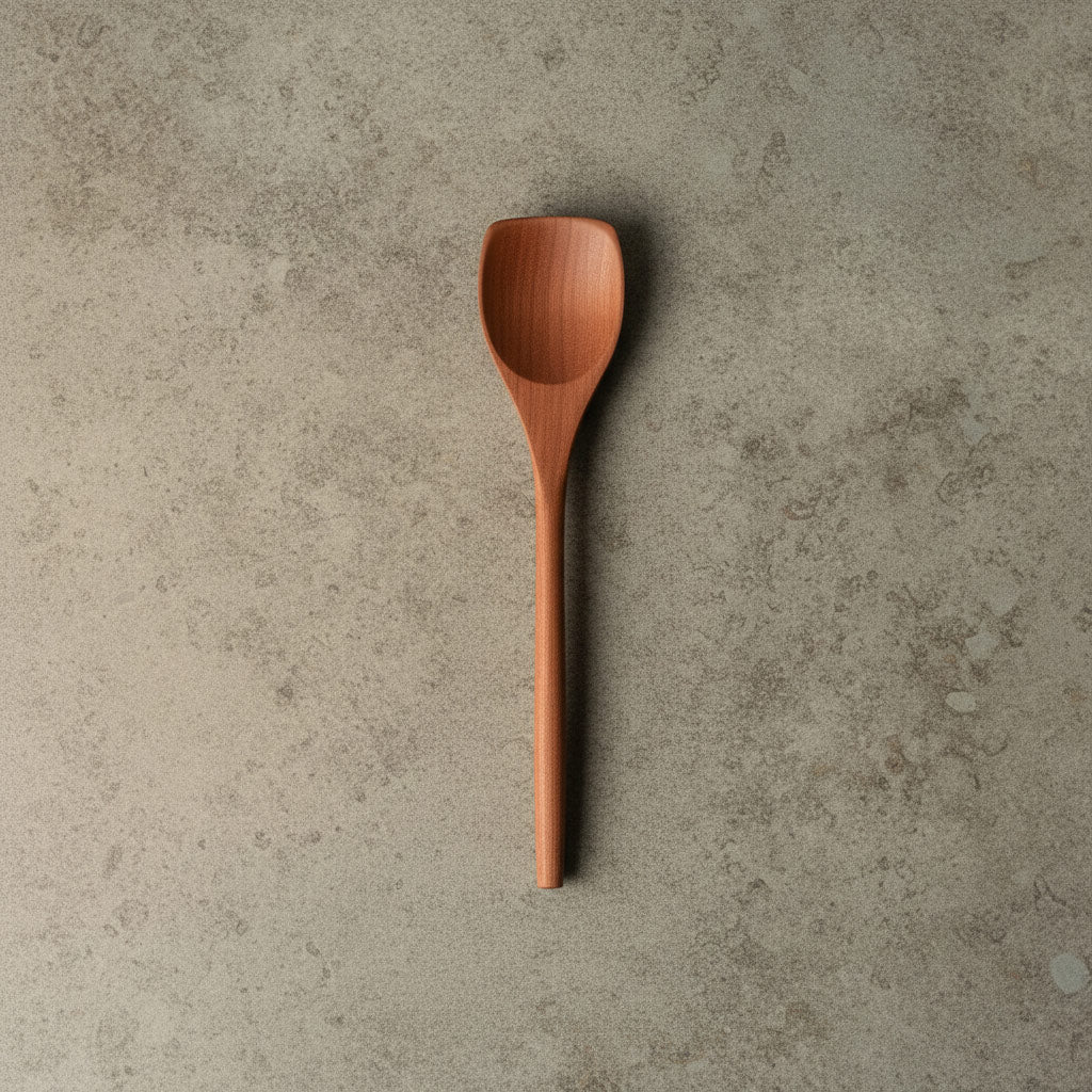 Handgefertigter Portionierlöffel aus Elsbeere, liegend in Draufsicht, mit elegant geschwungenem Design und glatter Oberfläche, nachhaltig produziert.