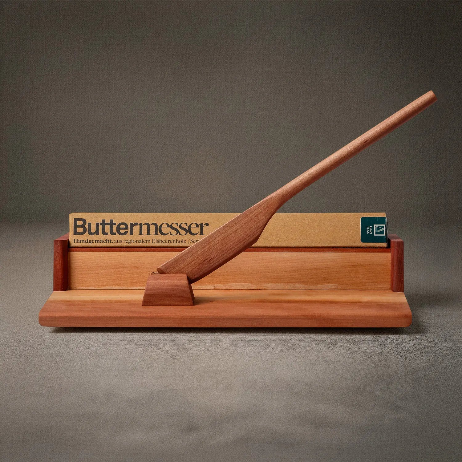 Buttermesser aus Holz, aus Elsbeerenholz gefertigt von Leipziger Tischlerei mimikry, auf dessen Aufsteller für manufactum