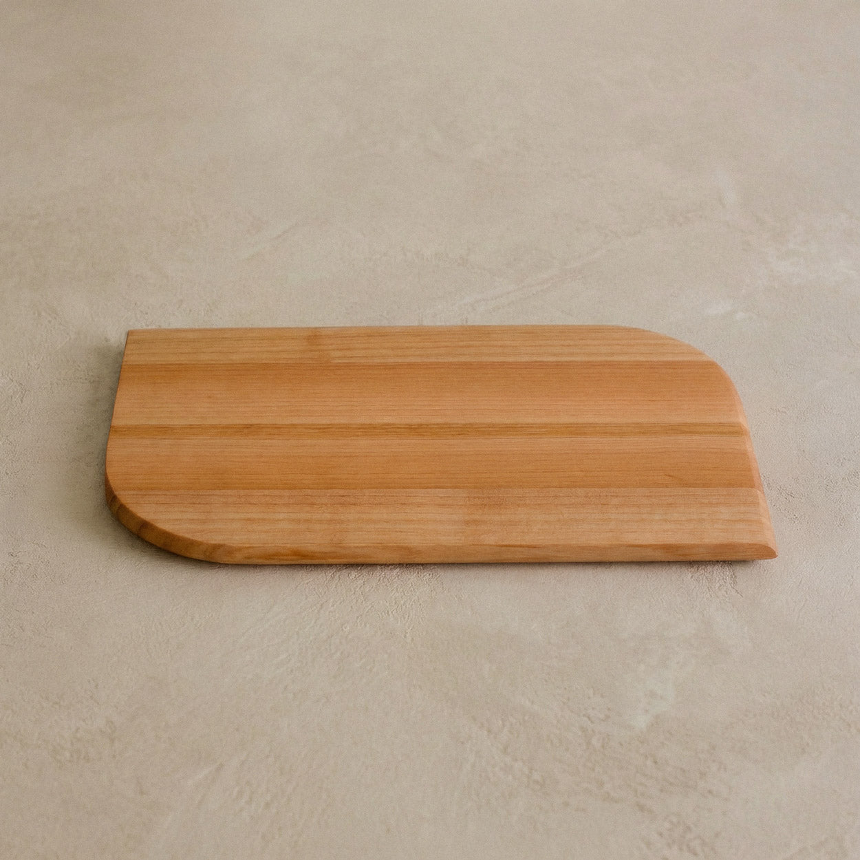 Kleines Schneidebrett aus einem Stück Talino Kirsche auf beigem Steinboden 01