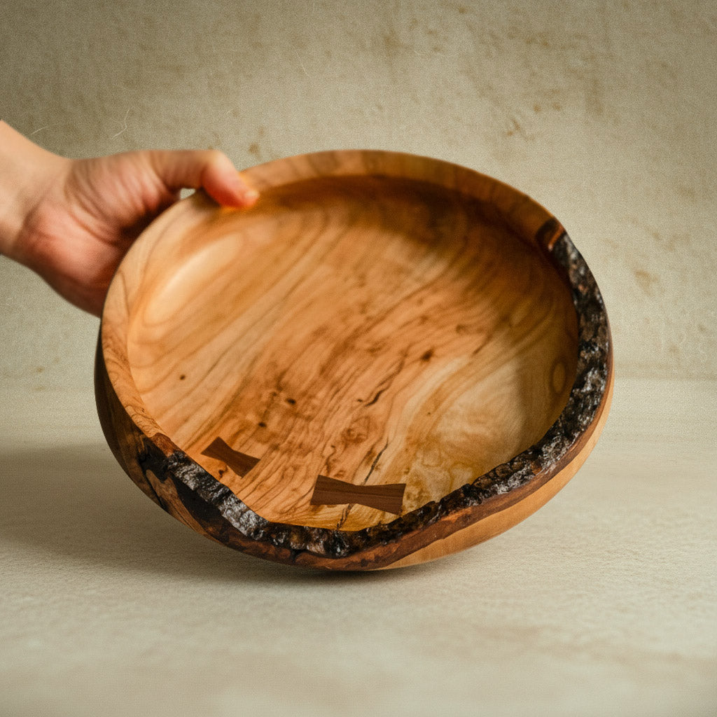 Hand hält eine handgefertigte Holzschale aus Kirschholz mit rustikalem Holzrand und einzigartiger Holzstruktur.
