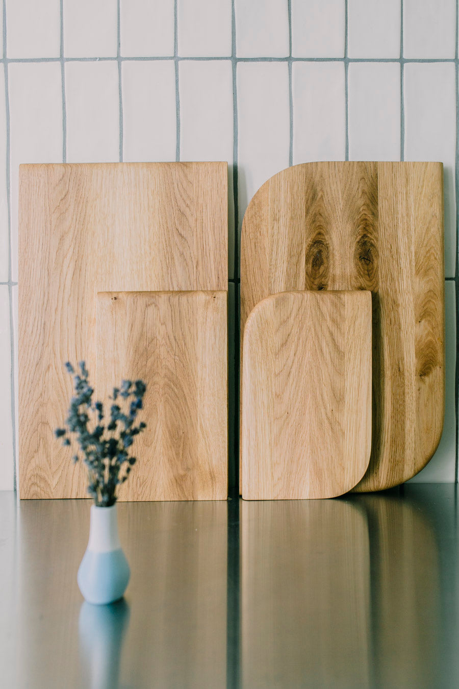 Zwei Holz Schneidebretter Varianten von mimikry im Vergleich, stehen nebeneinander auf einer Edelstahlarbeitsfläche. Davor ist Lavendel in einer Vase zu erkennen